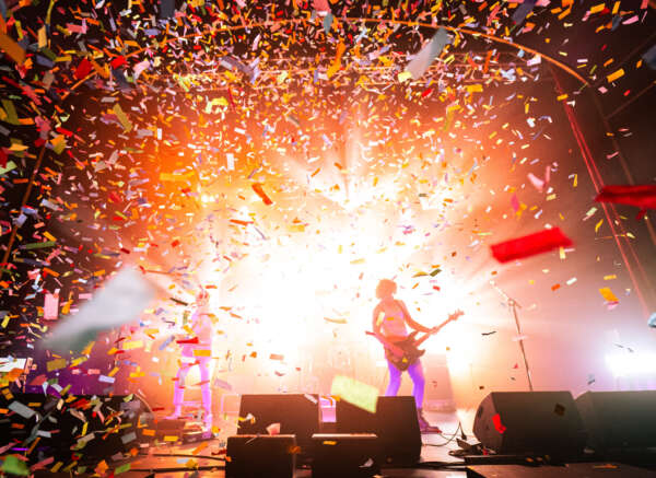Bugs band playing on stage behind an explosion of confetti